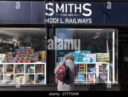 Una donna che guarda alla vetrina del negozio Smiths Model Railways, un tempo un hobby popolare; Sheringham, Norfolk, Inghilterra, Regno Unito Foto Stock