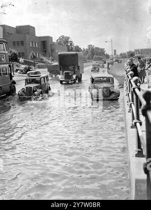 IL FIUME TRABOCCA DOPO LA TEMPESTA - AUTO ABBANDONATE IN PIENA dopo la terribile tempesta che si è rotta su Londra, il fiume Brent è traboccato causando un'inondazione sulla North Circular Road, Middlesex, dove l'aquaduct che trasportava il Regent's Canal passa sopra la strada. Le auto sono state rese impotenti nel tentativo di arare attraverso la carreggiata allagata. Spettacoli fotografici: Il traffico si ara attraverso l'acqua con sulla destra, un'auto abbandonata sulla North Circular Road, Middlesex. 27 luglio 1946 Foto Stock