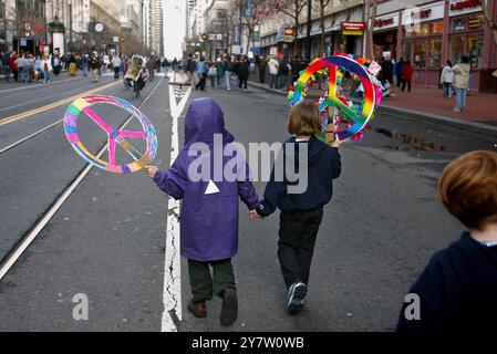 San Francisco, California... due giovani manifestanti si tengono per mano mentre portano i segni di pace domenica 16 febbraio 2003, mentre si uniscono a migliaia di attivisti in una marcia anti-guerra lungo Market Street. La marcia di protesta di San Francisco, tenutasi un giorno dopo manifestazioni simili in altre città del mondo, iniziò presso il Justin Herman Plaza e proseguì lungo Market Street prima di terminare al Civic Center Plaza. ( ) Foto Stock