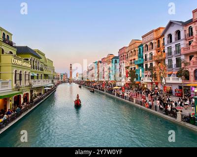 Nella scena del tramonto, una barca naviga nel mezzo del fiume, con case colorate su entrambi i lati. Scena al Mega Grand World Hanoi Foto Stock