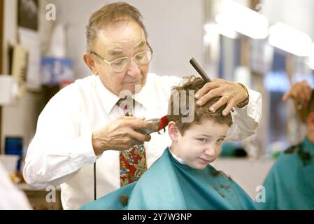 PALO ALTO, CALIF.,--Roy Ruiz lavora per dare a Ben Leonard, 6 anni, di Redwood City, un taglio di capelli mentre cerca di rimanere sveglio sabato 17 gennaio 2004. Il padre di Ben Trask si fa tagliare i capelli con Roy dal 1985 da quando era uno studente di Stanford. Il President Barber Shop che da allora si trova su University Avenue dalla fine degli anni '1920 Foto Stock