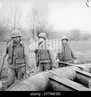 GLI ALLEATI INTENSIFICANO LE ESERCITAZIONI DI ATTRAVERSAMENTO DEL FIUME AD OVEST DEL RENO con le forze britanniche, canadesi e americane che si affacciano sul Reno da Arnhem a Coblenz, e la testa di ponte a Remagen che cresce ogni giorno, gli Alleati hanno integrato le esercitazioni di attraversamento del fiume ad ovest dell'ultima linea di difesa naturale della Germania sul fronte occidentale. Fotografie: Le truppe d'assalto del settimo esercito provano un fiume che attraversa il Reno ad ovest. Da sinistra a destra, portando il loro gommone, ci sono il soldato Osmus Leonard di prima classe del 322 Alameda avenue, Astoria, Oregon T/5 Elmore Scafibel, di Natalbany, Louisian, e il sergente George Prengress, di A. Foto Stock