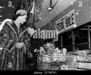 La regina Elisabetta guarda gli acquisti di un acquirente mentre visita un supermercato americano qui. Con il principe Filippo, la regina stava tornando da una partita di football americano quando ha fatto la visita a sorpresa al negozio. Lei e il Principe hanno camminato per 15 minuti chiacchierando con le ragazze delle vendite e gli acquirenti, Washington USA. (American Football Match ebbe luogo il 18 ottobre 1957) il 20 ottobre 1957 Foto Stock