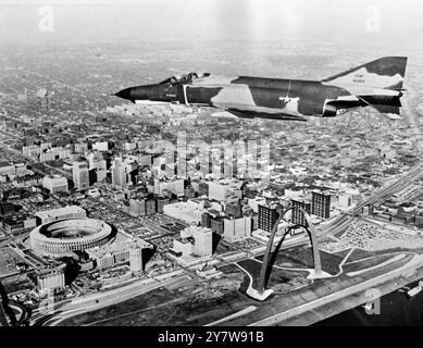 Il McDonnell-Douglas F-4E Phantom, la pistola più veloce del cielo, disegna una perla sul pittoresco lungomare di St Louis, ammirando il Gateway Arch (a destra) e il nuovo Busch Stadium (a sinistra). Il jet, il più recente della famosa serie Phantom, trasporta un cannone da 20 mm in una capsula bianca sotto il naso, oltre a missili guidati da radar e infetta missili rossi di altri Phantoms, St Louis, Missouri, USA.30 dicembre 1967 Foto Stock