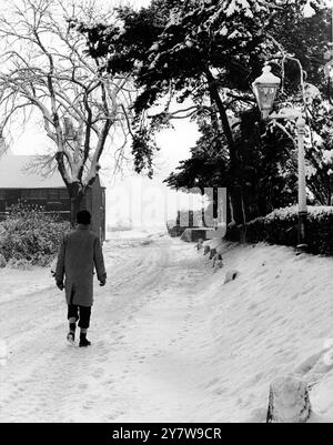 Un uomo che cammina lungo la strada innevata di Hook Place Farm , Southfleet , Kent , Inghilterra .3 febbraio 1962 Foto Stock