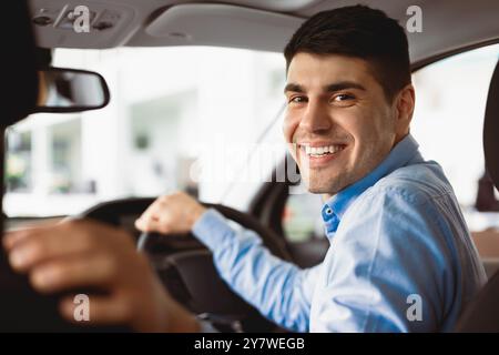 Happy Young Man seduto in auto nel Dealership Center Foto Stock