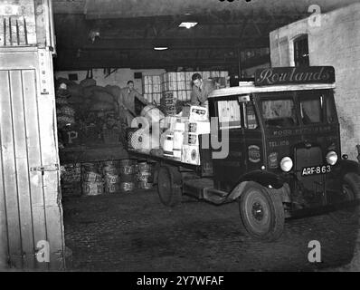 Rowlands - fornitori di generi alimentari che caricano il loro camion con greengrocery per la consegna . 1937 Foto Stock