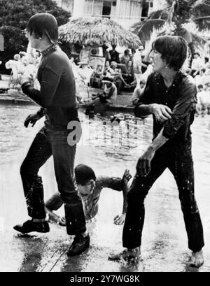 I Beatles - John Lennon, Paul McCartney e George Harrison ergono da una piscina bagnata dopo una nuotata completamente vestita come parte del loro nuovo film, ' Help! ', che stanno facendo alle Bahamas. 24 febbraio 1965 Foto Stock