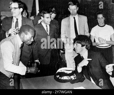 Paul McCartney con un cameriere che serve rinfreschi durante una conferenza stampa dopo l'arrivo dei Beatles a Nassau, Bahamas, 23 febbraio 1965 Foto Stock