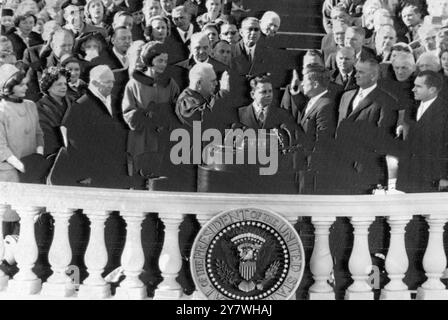 La scena nel ruolo di John F Kennedy è giurata come 35° presidente americano dal giudice della Corte Suprema Earl Warren (centro sinistro). Tra di loro c'è l'impiegato di corte James R Brown. A sinistra della foto (da sinistra a destra) ci sono la signora Jacqueline Kennedy, la signora Mamie Eisenhower e il presidente uscente Dwight Eisenhower. All'estrema destra ci sono i due vicepresidenti, Lyndon B Johnson (accanto a Kennedy) e Richard Nixon . Sfondo a sinistra (alto in uniforme) è il figlio del presidente uscente, il maggiore John Eisenhower. 20 gennaio 1961 Foto Stock