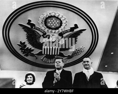 Sotto il sigillo degli Stati Uniti , il Presidente John F Kennedy plaude ad uno dei carri della Inauguration Parade di Washington del 20 gennaio 1961 . Sulla sinistra si trova Jacqueline , la moglie del Presidente , e sulla destra c'è il Vice Presidente Lyndon B Johnson Foto Stock