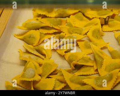 Mantova, Italia 30 settembre 2024 ravioli triangolari crudi con ripieno di spinaci appoggiati su carta bianca pergamena prima di essere cotti Foto Stock