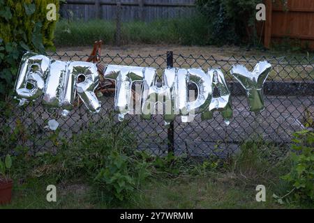 Silver Happy Birth Words fatto di palloncini gonfiabili sul recinto del giardino in inghilterra regno unito. Foto Stock