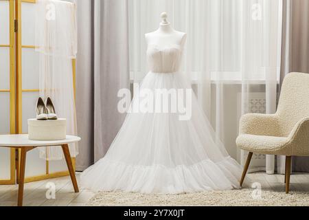 Bellissimo abito da sposa con manichino e scarpe in boutique Foto Stock