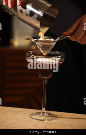 Barman che prepara deliziosi martini espresso al tavolo di legno del bar, primo piano Foto Stock