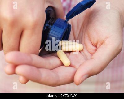 Una donna che prende capsule del complesso di vitamina B da un flacone. Primo piano. Foto Stock