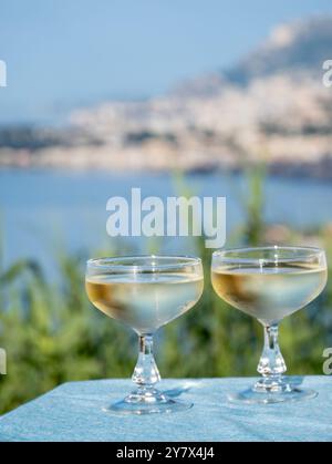 Spumante freddo, cava o champagne in due bicchieri da coupé sul tavolo con vista mare vicino a Mentone e Monte Carlo, Costa Azzurra, la Francia è estate Foto Stock