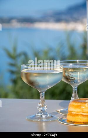 Spumante freddo, cava o champagne in due bicchieri da coupé sul tavolo con vista sul mare blu vicino a Mentone e Monte Carlo, Costa Azzurra, la Francia è estate Foto Stock