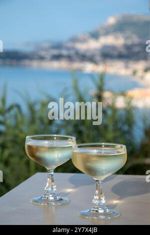 Spumante freddo, cava o champagne in due bicchieri da coupé sul tavolo con vista sul mare blu vicino a Mentone e Monte Carlo, Costa Azzurra, la Francia è estate Foto Stock