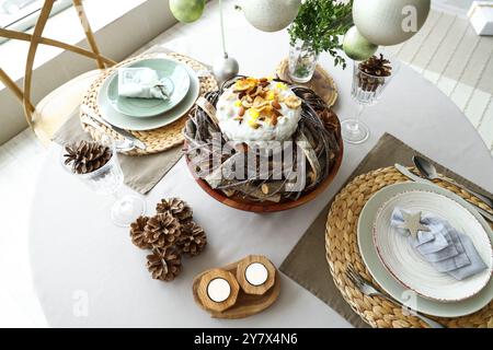 Tavolo festivo per la cena di Natale con torta, candele accese e coni di pino Foto Stock