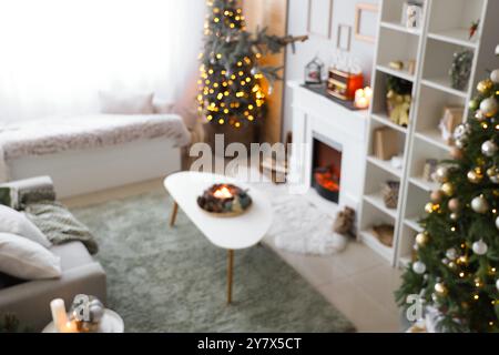 Vista sfocata del soggiorno festivo con arredi natalizi, tavolino da caffè e caminetto Foto Stock