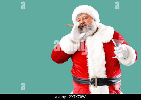 Babbo Natale cattivo con sigaro e cocktail su sfondo verde Foto Stock