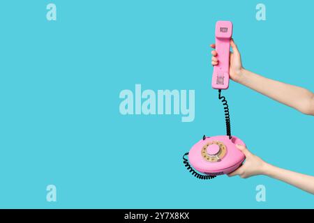 Mani femminili con retro-telefono su sfondo blu Foto Stock