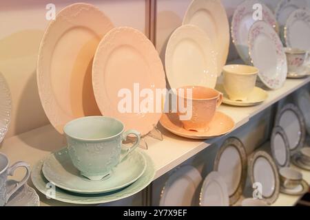 Piatti e tazze in ceramica colorata in fila sugli scaffali dei negozi Foto Stock