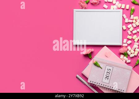 Cornice fotografica con quaderno e fiori su sfondo rosa Foto Stock