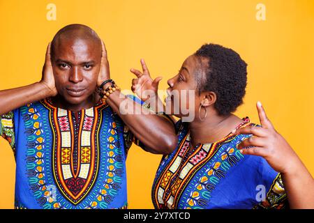 Coppia nera in relazione in lotta con un concetto di disputa familiare. Infastidita donna afroamericana che urlava mentre infelice frustrato uomo che chiude le orecchie con le braccia e guarda la macchina fotografica Foto Stock