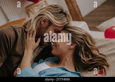 Primo piano di una felice coppia amorevole che abbraccia e sorride mentre si sdraia a letto a casa Foto Stock