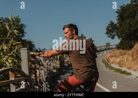 Giovane e sicuro in bicicletta riposato dopo aver fatto una passeggiata in bicicletta lungo la strada panoramica Foto Stock