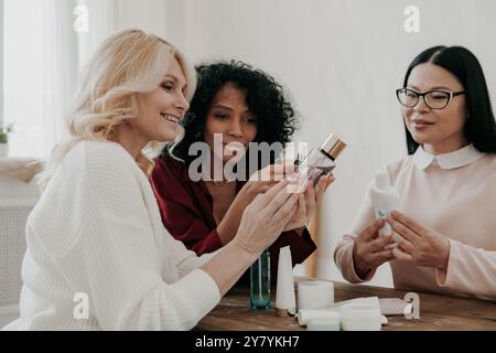Tre donne mature che esaminano trattamenti di bellezza sedute alla scrivania insieme Foto Stock