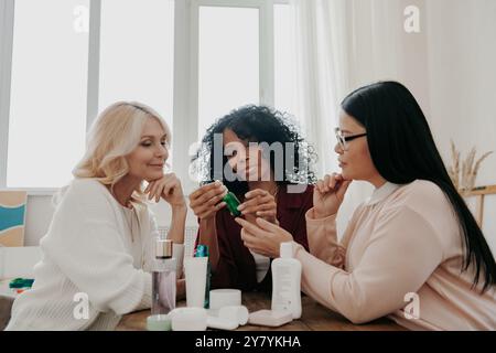 Tre donne mature che esaminano trattamenti di bellezza sedute alla scrivania insieme Foto Stock