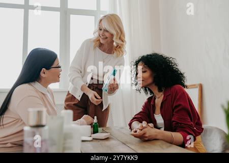 Tre donne mature felici che esaminano i prodotti di bellezza mentre sono sedute alla scrivania insieme Foto Stock