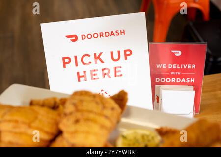 Los Angeles, California, Stati Uniti - 02-24-2021: Una vista di un DoorDash pick up qui firma su un tavolo, e cibo in primo piano. Foto Stock