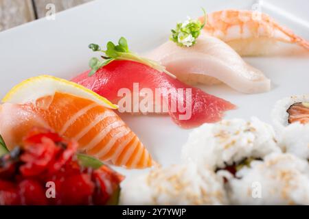Vista ravvicinata di un piatto con nigiri, come salmone, tonno, coda gialla e gamberi. Foto Stock