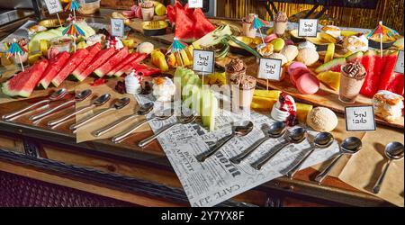 Un piatto di frutta colorata con anguria, ananas, dessert e piccoli ombrelli decorativi, perfetto per una rinfrescante delizia estiva. Ebraico Foto Stock
