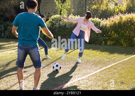 Giocare a calcio all'aperto, la famiglia asiatica si diverte a giocare insieme nelle giornate di sole Foto Stock
