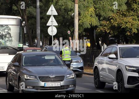 DNIPRO, UCRAINA - 01 OTTOBRE 2024 - Un poliziotto blocca il traffico durante un minuto di silenzio a livello nazionale in memoria dei soldati caduti in occasione della giornata dei difensori dell'Ucraina, Dnipro, Ucraina orientale Foto Stock