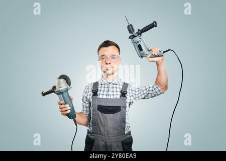 Ritratto di un Handyman che tiene gli utensili elettrici in entrambe le mani Foto Stock