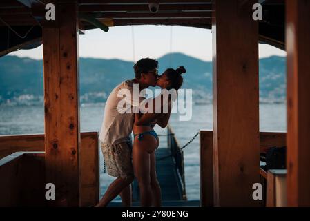 Un tenero bacio romantico condiviso tra una coppia su una barca durante un tramonto mozzafiato Foto Stock