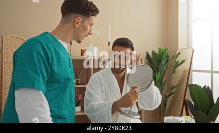 Terapeuta che interagisce con un paziente nella spa indossando l'accappatoio che tiene lo specchio nel centro benessere interno Foto Stock