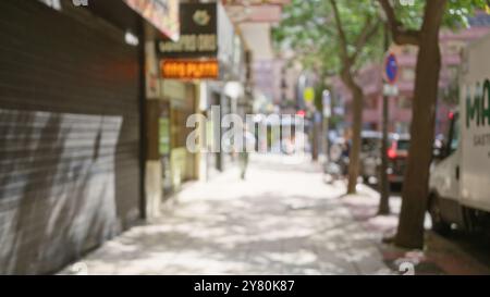 Vista sfocata di una trafficata strada all'aperto con persone, alberi ed edifici sullo sfondo durante il giorno, creando un'atmosfera urbana sfocata Foto Stock