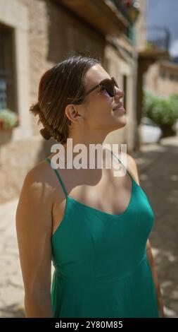 Donna che si gode la giornata di sole all'aperto a valldemossa, maiorca, spagna, indossando occhiali da sole e un abito verde Foto Stock