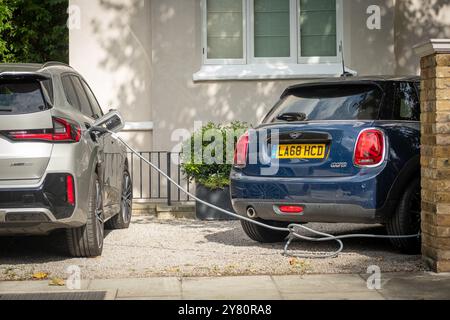 LONDRA - 9 AGOSTO 2024: Auto elettrica ricaricata fuori casa in un tipico ambiente residenziale di periferia britannica Foto Stock