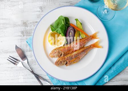 Triglia grigliata con rucola e mini verdure su un piatto di porcellana bianca Foto Stock