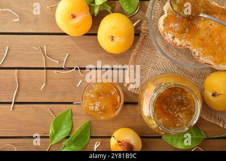 Colazione con marmellata di prugne naturali e fatte in casa con toast e marmellata spalmata su un piatto di legno con ciotola di vetro su un tavolo di legno con pezzi di frutta e lasciare Foto Stock