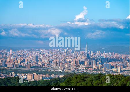 Una vista panoramica mozzafiato di una vivace città al tramonto. Le morbide e soffici nuvole attraversano il cielo, proiettando un caldo bagliore sul paesaggio urbano. CA Foto Stock