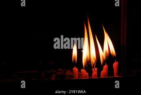 Primo piano incendiante lume di candela giallo su una scatola di sabbia su sfondo scuro, facendo merito, fede o credenza, preghiere con rispetto, concetto pacifico, religione Foto Stock